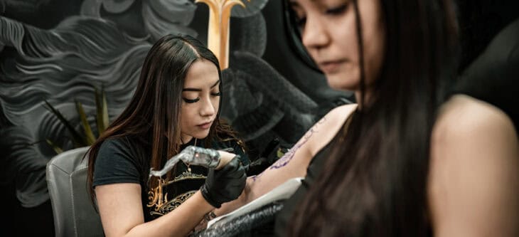 Tattoo artist creating art on client arm