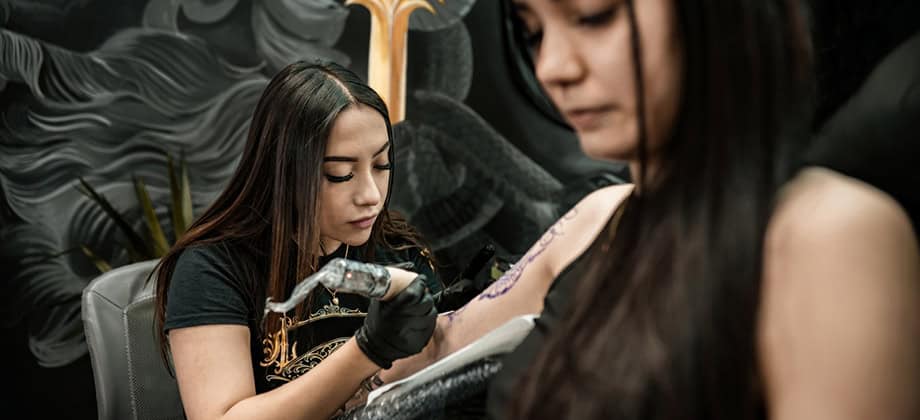 Tattoo artist creating art on client arm