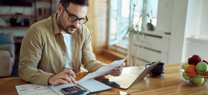 Young man working on his financial bills at home.