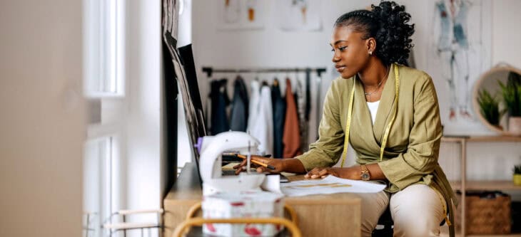 Young female clothing designer drawing sketches at workshop