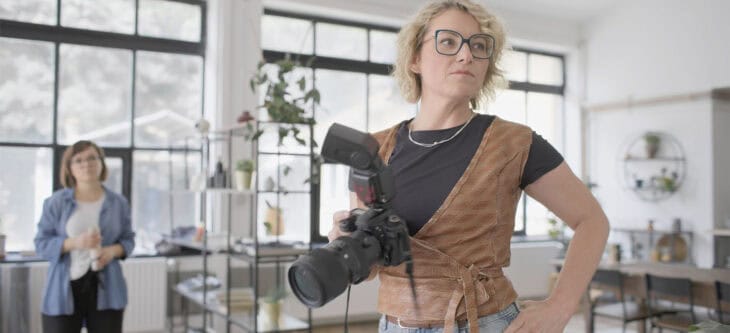 Professional Female Photographer With Camera In Modern Studio Space During Photo Session