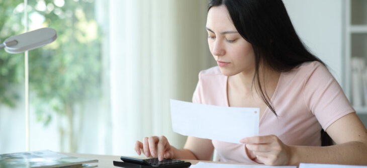 Woman calculating invoices at home